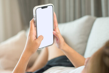 Close up image of young girl holding and sitting on sofa and using smartphone device, female hands typing text message via cellphone, social networking concept.