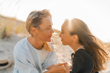 Outdoor   portrait  of beautiful family. Mother and doughter posing on the beach. Warm sunset colors.