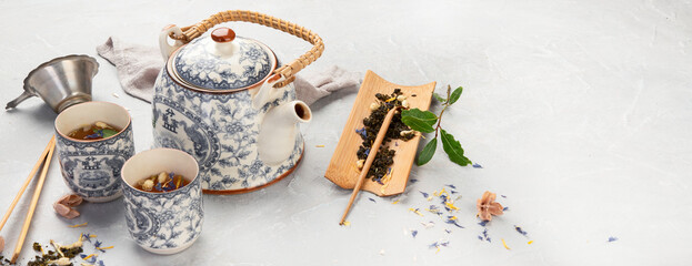 Asian teapot with herbal tea on light background.