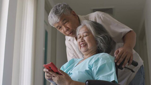 An Asian senior adult woman and her husband making a video call on a mobile phone to relatives after making a good recovery in the hospital. Concept hospital care