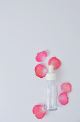 Empty serum bottle mock up with pink rose petal spreading around in white background