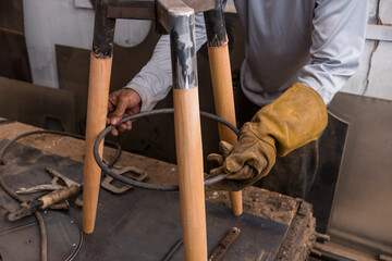 A carpenter inserting and affixing a steel ring unto a tripod bar stool. Custom furniture...