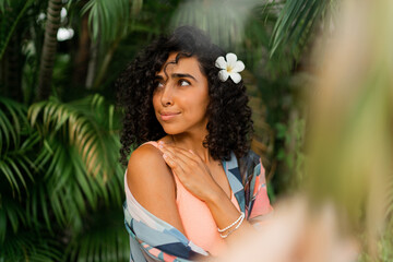 Close up portrait of  blissful woman with  plumeria flower in hairs after spa in   luxury resort. Wearing boho tropical outfit.
