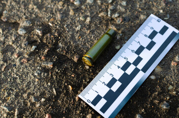 empty cartridge at the crime scene against the background of a forensic ruler