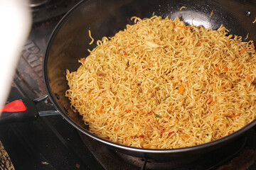closeup, fried yellow noodles in a frying pan. Indonesian instant noodles. selective focus