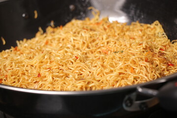 closeup, fried yellow noodles in a frying pan. Indonesian instant noodles