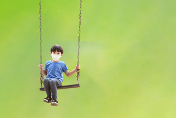 Portrait of Asian child sitting on swing happy on natural green background. children having fun on summer vacation dreams and imagination