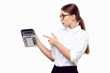 Upset surprised young female accountant pointing finger at calculator on white Isolated on background