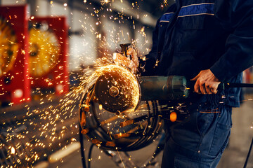 Close up of metallurgist grinding metal framework in factory.