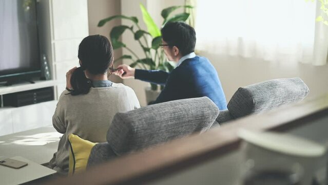 ソファーに座ってテレビをみる夫婦