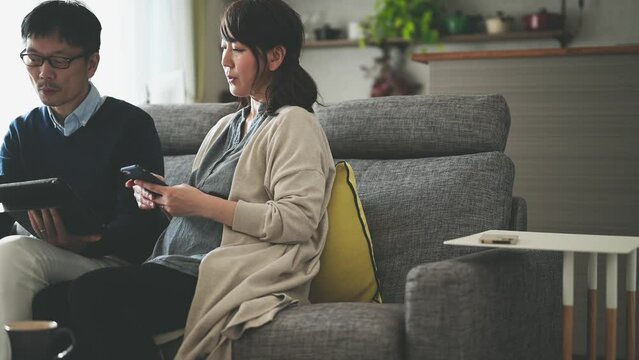 デジタル端末の操作をする妊娠している夫婦	