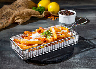 Truffle Fries in deep fryer dish side view on dark background fast food