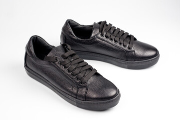 Black imitation leather shoes laced with wide laces. Close-up shot.