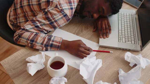 Exhausted bored lazy overworked businessman at home office falling asleep on table with laptop computer and crumpled sheets of paper. Guy feeling lack of energy after sleepless restless workday