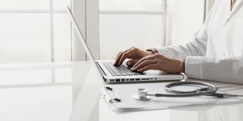 Doctor medical professional working on laptop computer. Physician, therapist or practitioner filling medical document, writing prescription for patient. Healthcare, medicine, medical insurance concept