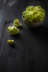 Ripe green cauliflower on a plate. Dark wood background.