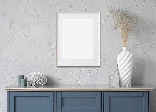 Blank frame mockup in modern interior design with blue sideboardand and flowers on empty gray wall background. Single vertical template for painting or poster. Artwork mock-up