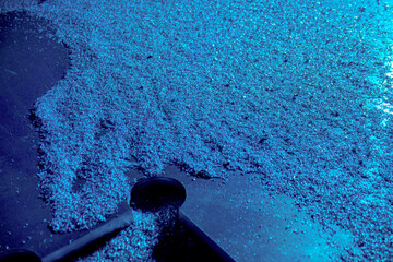 Particles of shiny chips after working out drilling, milling or turning machine in production or factory. Steel scrap materials recycling. Close up of metallic dust in blue light.