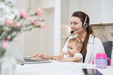 Pleased woman using laptop keyboard with baby daughter