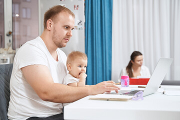 Fototapeta na wymiar Father working from home with child on his knees