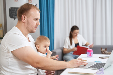 Man moving hand on laptop touchpad while baby looking