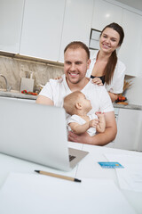Male doing distance job on laptop with wife and daughter