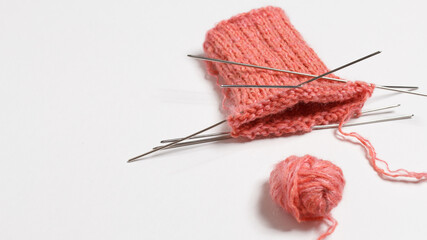 wool product and knitting needles on a white background. the process of knitting from yarn