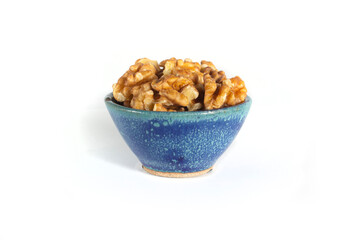 Walnut Halves and Pieces in Small Blue Pottery Bowl Isolated on White