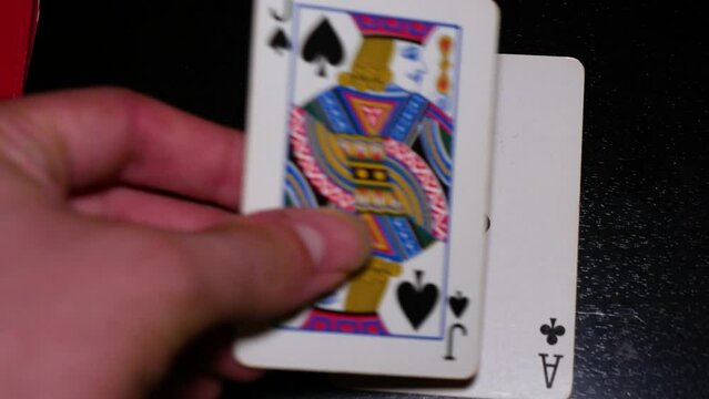 A hand of perfect blackjack is dealt with white cards on a black table. Filmed from above the cards
