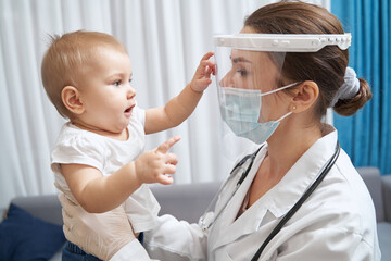 Physician raising kid, who touching her face shield