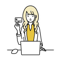 デスクで座ってPCを使いながらクレジットカードを手に持っているジャケットの女性