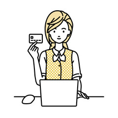 デスクで座ってPCを使いながらクレジットカードを手に持っている事務員制服の女性