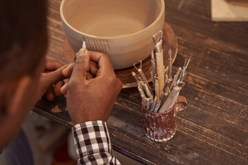 Experienced potter making designs on earthenware with ceramic tool
