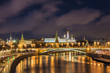 Illuminated Moscow Kremlin and Bolshoy Kamenny Bridge in the night. View from the Patriarshy pedestrian Bridge in Russia. Evening urban landscape in the blue hour