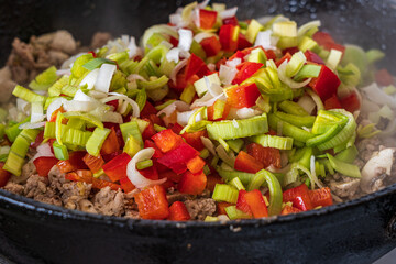 Sliced vegetables and meat in a frying pan.