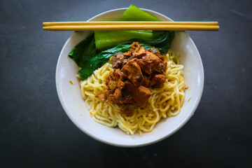 mie ayam or chicken noodle  with meatball served on small bowl
