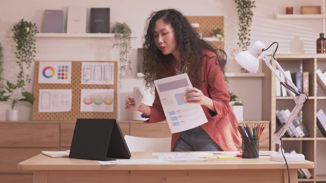 Asian Designer woman work from home and communicate with the design team over the internet. On a teblet,women are having a video conference call.