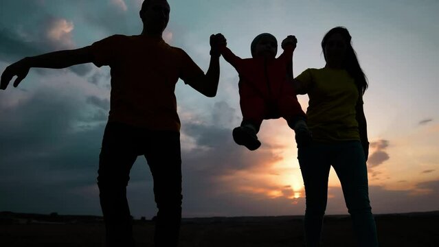 happy family. father mother and baby run play at sunset silhouette holding hands and throw up. happy family in kid dream park fun concept. baby and parents family run together silhouette in the park