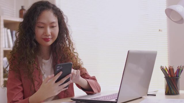 Asian woman waving a smartphone app enjoys online virtual video chat with pals in a virtual meeting while sharing stories for social media.