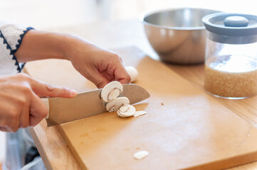 カッティングボードでマッシュルームをカットする女性の手元