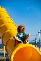 Obraz premium Child on slide playground area. Child in park on summer day, having fun smiling outdoors. Kids enjoying playing activities, leisure recreation lifestyle.