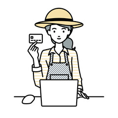 デスクで座ってPCを使いながらクレジットカードを手に持っている農家の女性