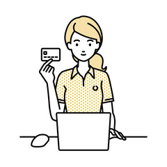 デスクで座ってPCを使いながらクレジットカードを手に持っているドレスの女性