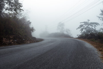 Asphalt road in a fog in the mountains
