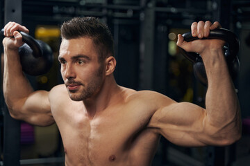 Fototapeta na wymiar Handsome male athlete holding weights in both hands