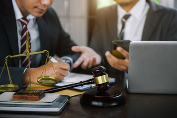 Close up view of auction hammer on the desk in lawyer office and lawyer writing document as courtroom.