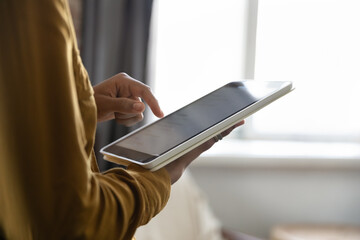 Black woman using online app, virtual service on tablet computer, touching, swiping touchscreen, shopping on Internet, browsing, paying for purchase. Cropped shot, hand holding gadget, screen close up