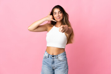 Young caucasian woman isolated on pink background making phone gesture and pointing front