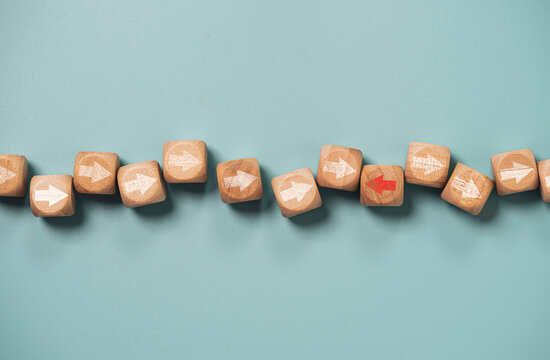 Disruption and technology transformation concept , Red arrow on wooden block cube move  in opposite direction from red arrow on blue background.