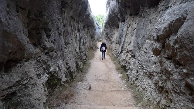 Woman walking between vertical rock walls in the Ciudad Encantada natural park, Cuenca.